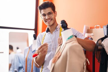 Genç İspanyol terzi atölyedeki manikine ceket dikiyor.