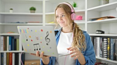 Kütüphanede videolu görüşme yapan genç sarışın kız öğrenci.