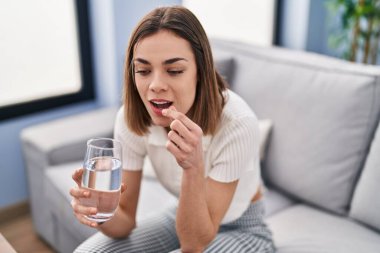 Evdeki kanepede oturup hap alan genç, güzel İspanyol kadın.