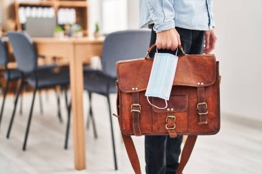 Ofiste tıbbi maske ve evrak çantası tutan İspanyol bir iş adamı.