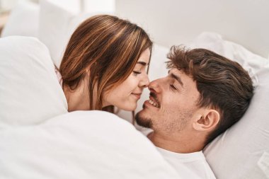 Mand and woman couple smiling confident lying on bed at bedroom