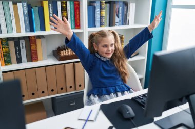 Sınıfta bilgisayar kullanan sevimli sarışın kız öğrenci.