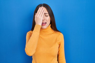 Genç esmer kadın mavi arka planda duruyor. Yüzünün yarısını, gözünü ve ağzını eliyle kapatmaktan yoruluyor. Yüzüm acıyor.. 