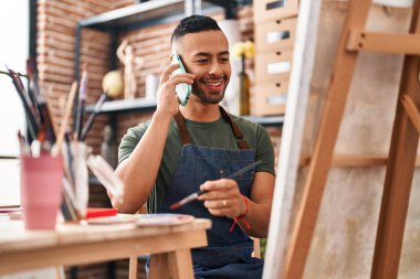 Sanat stüdyosunda Afrikalı Amerikalı sanatçı akıllı telefondan resim çiziyor.