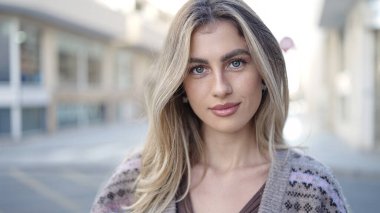 Sokakta ciddi bir ifadeyle duran genç sarışın kadın.