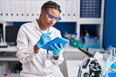 African american woman scientist using touchpad at laboratory