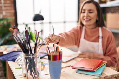 Sanat stüdyosunda not defterine çizim yapan orta yaşlı kadın sanatçı.
