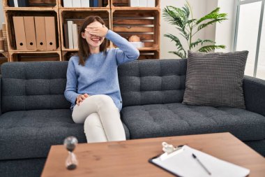 Muayenehanedeki genç esmer kadın şaşkınlıktan gözleri kapayarak gülümsüyor ve gülüyor. kör kavram. 