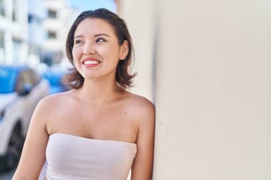 Genç İspanyol kadın gülümsüyor. Kendine güveni tam. Caddeye bakıyor.