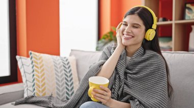 Genç, güzel İspanyol kadın evde kahve içerek müzik dinliyor.