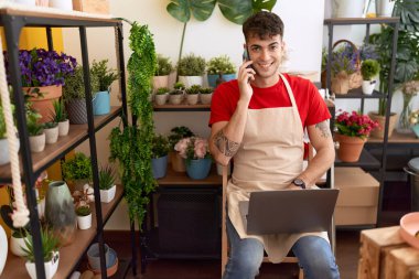 Çiçekçide dizüstü bilgisayar kullanarak konuşan İspanyol çiçekçi.