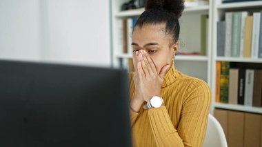 Genç Afro-Amerikan bayan öğrenci kütüphanede bilgisayar kullanıyor.