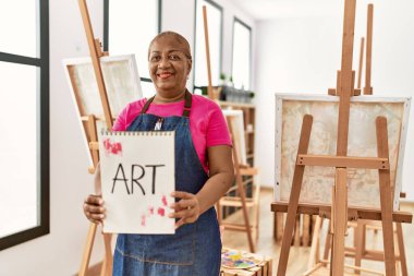 Sanat stüdyosunda resim çizen yaşlı Afro-Amerikan kadın.