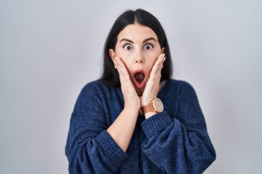 Genç esmer kadın izole edilmiş arka planda duruyor. Korkmuş ve şok olmuş halde. Şaşırmış ve şaşırmış bir halde. 