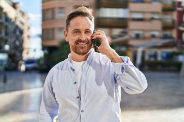 Kafkasyalı genç adam gülümsüyor. Kendine güvenen caddedeki akıllı telefondan konuşuyor.