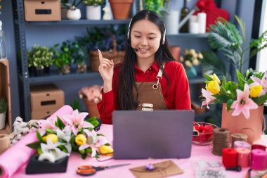 Çiçekçide çalışan Asyalı genç bir kadın. Video çekiyor. Gülümsüyor. 