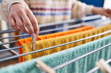 Çamaşır odasında çamaşır ipine elbise asan beyaz bir kadın.