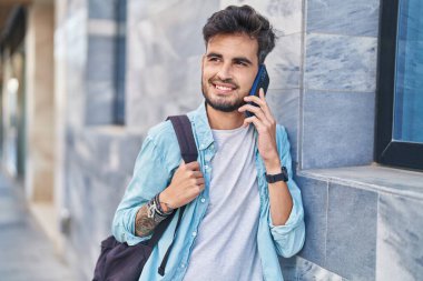 İspanyol asıllı genç bir öğrenci gülümsüyor. Akıllı telefondan konuşuyor.