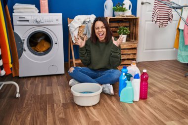 Genç İspanyol kadın çamaşırları elleriyle yıkıyor zaferi kutluyor mutlu bir gülümsemeyle ve ellerini kaldırarak kazanan bir ifadeyle. 