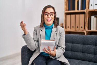 Orta yaşlı kadın psikolog, psikoloji merkezinde kendinden emin bir şekilde gülümsüyor.