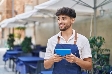 Young arab man waiter using touchpad working at restaurant