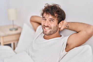 Young man smiling confident relaxed on bed at bedroom