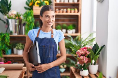Young beautiful hispanic woman florist smiling confident holding binder at florist