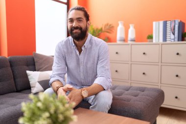 Evdeki kanepede kendinden emin gülümseyen İspanyol genç adam.