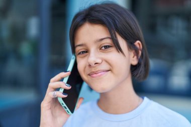 Sevimli İspanyol kız gülümsüyor. Kendine güveni tam. Sokakta akıllı telefondan konuşuyor.