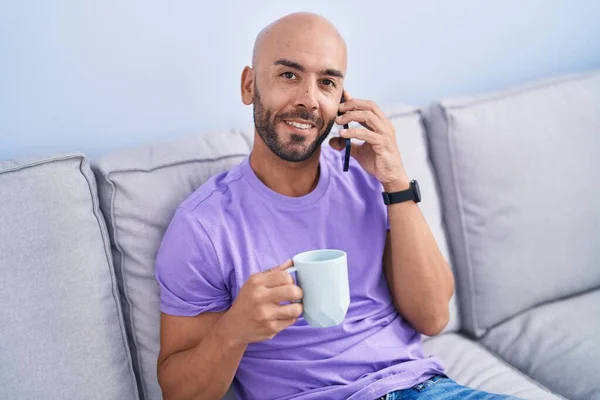 年轻的秃头男人在家里用智能手机喝咖啡 — 图库照片