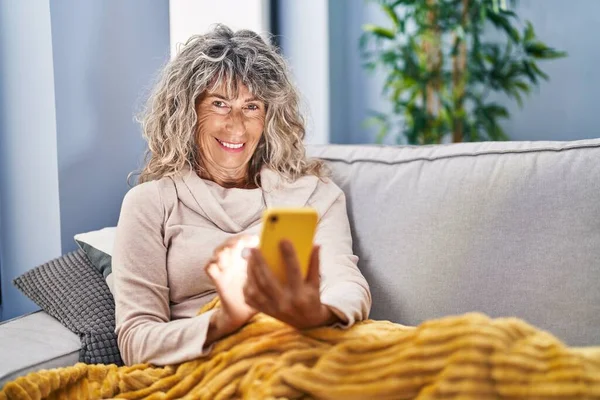 Frau Mittleren Alters Sitzt Mit Smartphone Hause Auf Sofa — Stockfoto
