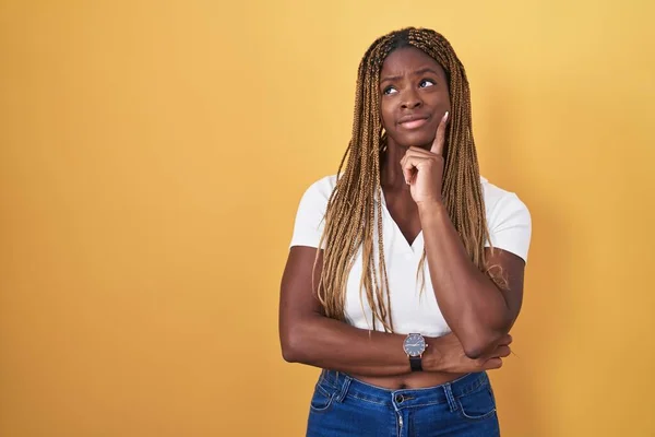 Africká Američanka Copánky Stojící Nad Žlutým Pozadím Přemýšlející Otázce Znepokojená — Stock fotografie