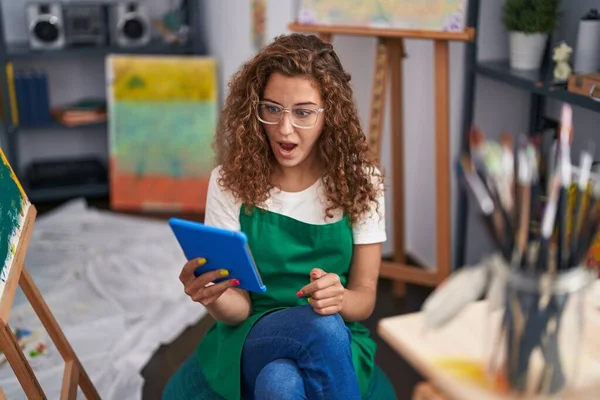 年轻的高加索女画家坐在艺术工作室里 用平板电脑做视频通话 惊讶地张开嘴 惊讶地惊讶地 难以置信地看着 — 图库照片