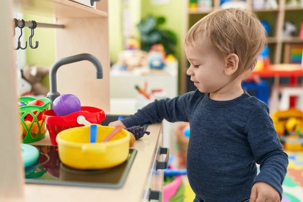 stock image Adorable blond toddler playing with play kitchen standing at kindergarten