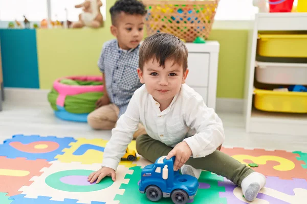 可爱的男孩子们坐在幼儿园的地板上玩汽车玩具 — 图库照片