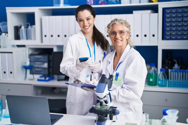 stock image Two women scientists using smartphone working at laboratory