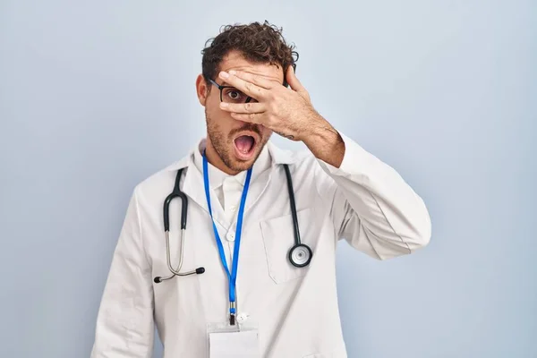 Young Hispanic Man Wearing Doctor Uniform Stethoscope Peeking Shock Covering — Stock Photo, Image