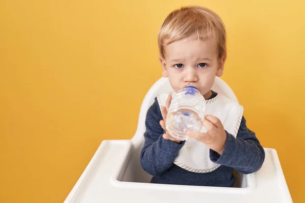 Adorable Blond Toddler Sitting Highchair Drinking Water Isolated Yellow Background — Stock Photo, Image