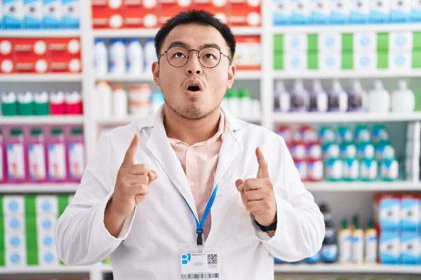Jovem Chinês Trabalhando Farmácia Farmácia Surpreendido Surpreso Olhando Para Cima — Fotografia de Stock