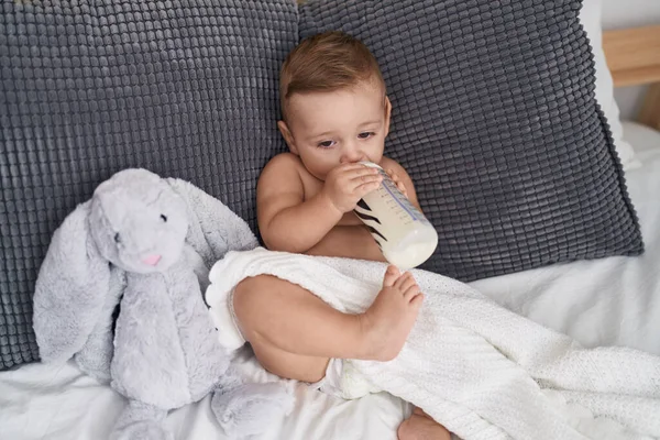 愛らしいCaucasian赤ん坊吸いミルクオン給餌ボトル上のソファに家に座って — ストック写真