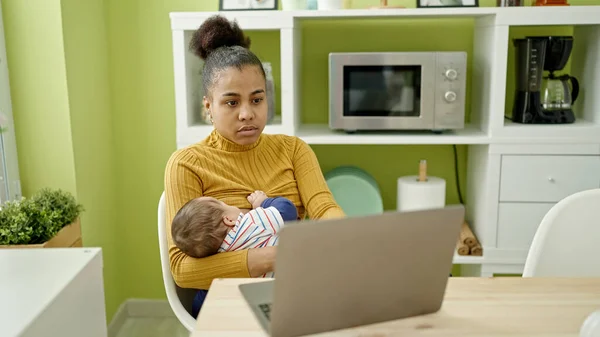 母亲和儿子是在网上工作的商人 他们在餐厅里给婴儿喂奶 — 图库照片