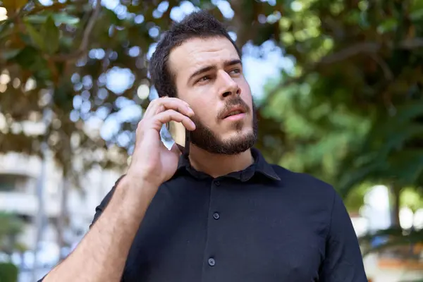 Joven Hombre Hispano Hablando Smartphone Con Expresión Relajada Parque — Foto de Stock