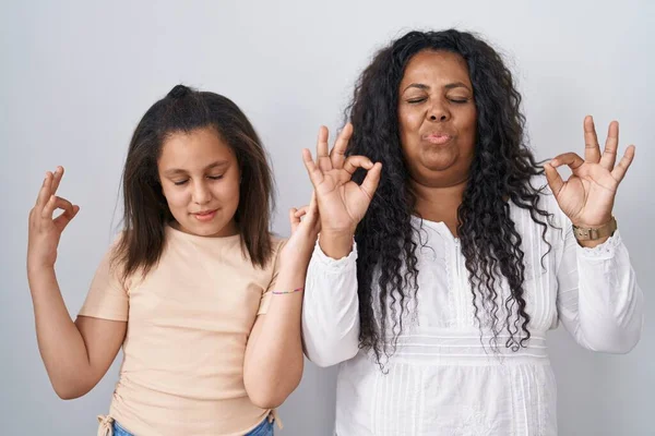 母亲和年轻的女儿站在白色的背景上 放松地微笑着 闭上眼睛 用手指做冥想的姿势 瑜伽概念 — 图库照片