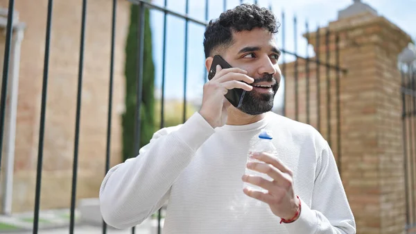 Joven Hispano Sosteniendo Botella Agua Hablando Smartphone Calle — Foto de Stock
