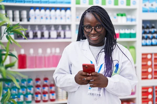 薬局で働くスマートフォンを使ったアフリカ系アメリカ人女性薬剤師 — ストック写真