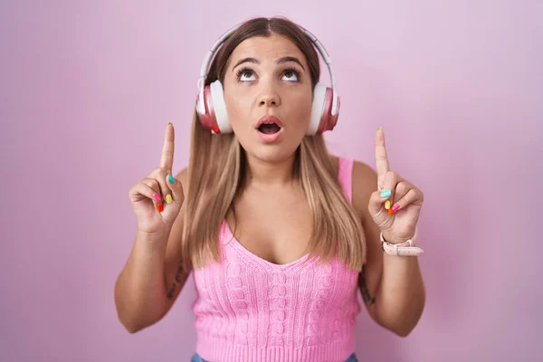 Mladá Blondýnka Poslouchající Hudbu Pomocí Sluchátek Užaslá Překvapená Vzhlížející Ukazující — Stock fotografie