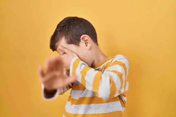 Sarı Arka Planda Dikilen Beyaz Bir Çocuk Elleriyle Gözlerini Kapatıyor — Stok fotoğraf
