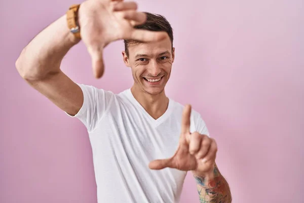 Homem Caucasiano Sobre Fundo Rosa Sorrindo Fazendo Moldura Com Mãos — Fotografia de Stock