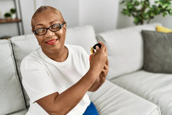 シニアアフリカ系アメリカ人女性使用香水座っています上のソファに家 — ストック写真