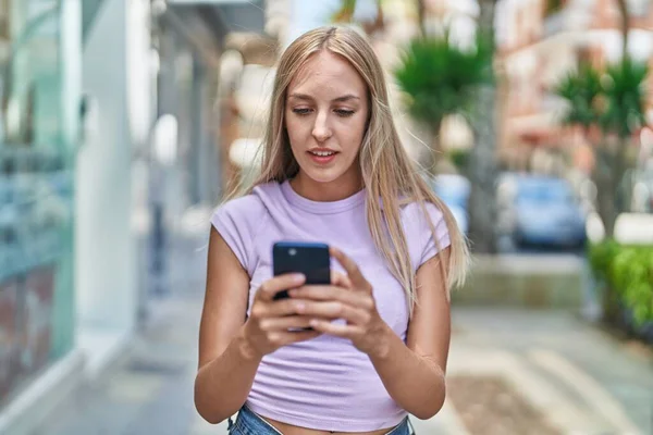 Νεαρή Ξανθιά Γυναίκα Που Χρησιμοποιεί Smartphone Χαλαρή Έκφραση Στο Δρόμο — Φωτογραφία Αρχείου
